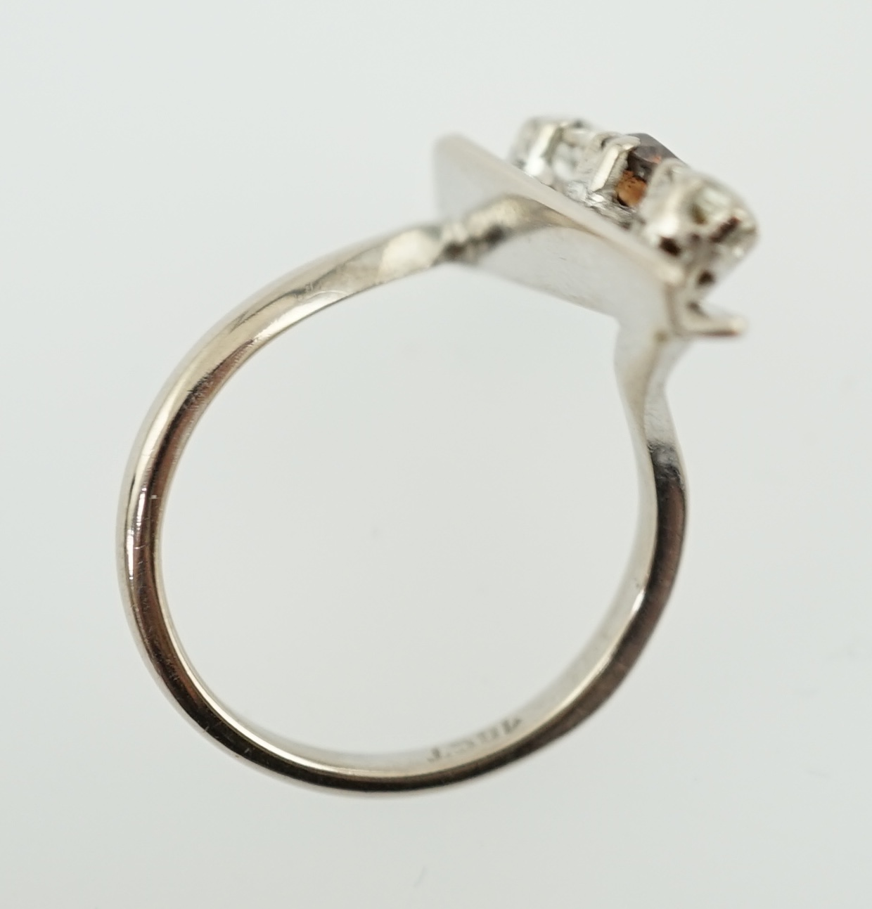 A 1970's 18ct white gold and graduated three stone diamond modernist ring